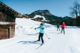 Famille de skieurs sur une piste de ski nordique au Grand-Bornand, près de chalets